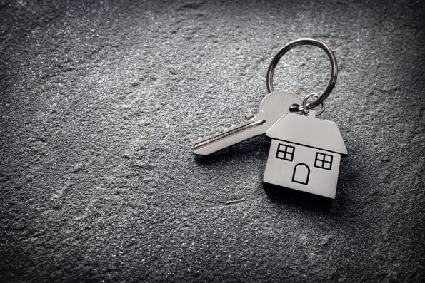 House key on a house shaped keychain on stone concept for real estate, moving home or renting property
