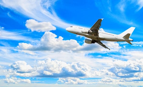 Airplane flying in the sky - travel background with white airplane. Commercial airplane, airplane travel concept. Airplane with blank livery, airplane in the flight. Travel landscape with flying airplane