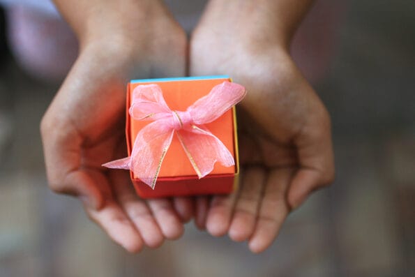 Hands holding an orange gift box. Life is a gift concept. Birthday gift. Valentine gift. Personal Gift. Mothers Day gift. Christmas gift. Thanksgiving and life appreciation concept.