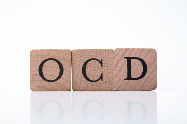 Close-up Of Ocd Text On Wooden Block Over Reflective Desk