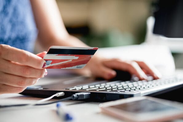 Woman buying online with credit card. Online shopping. Woman shopping online. Female hands holding credit card using laptop computer to shop online. Online shopping. Paying with credit card online.