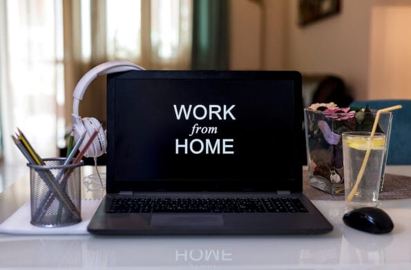 Work from home during Coronavirus pandemic quarantine isolation. Working remotely home concept. Comfortable working place in home office with laptop on the table with Headphones, lemonade and office stuff. Work from Home on the laptop screen