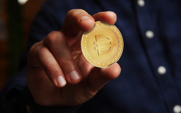 Dai stablecoin cryptocurrency symbol golden coin in hand abstract concept.