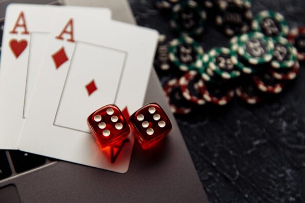 Chips, red dices and playing cards with aces for poker online or casino gambling on laptop keyboard close-up. Online casino concept
