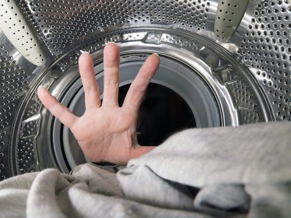 Unknown woman puts the laundry in the washing machine, inside the washing machine, closeup