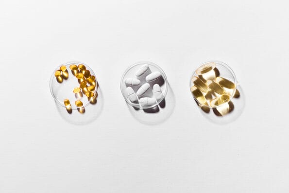 Vitamins capsules on white background, top view, copy space. Food supplements: fish oil, omega 3, omega 6, omega 9, vitamin A, vitamin D3, vitamin E, calcium.