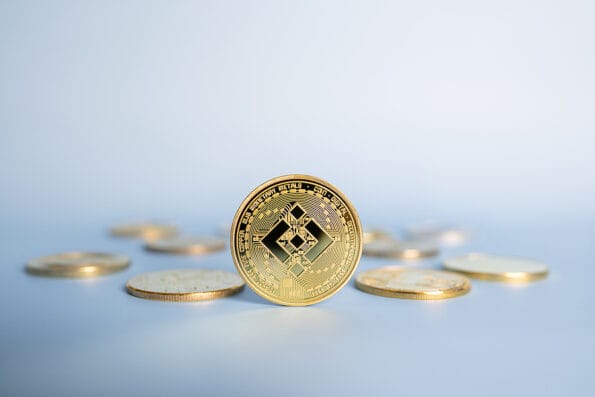 Binance BNB coin standing centrally placed among bunch of crypto gold coins on blue background. Close-up, soft focus. Token created by cryptocurrency exchange Binance