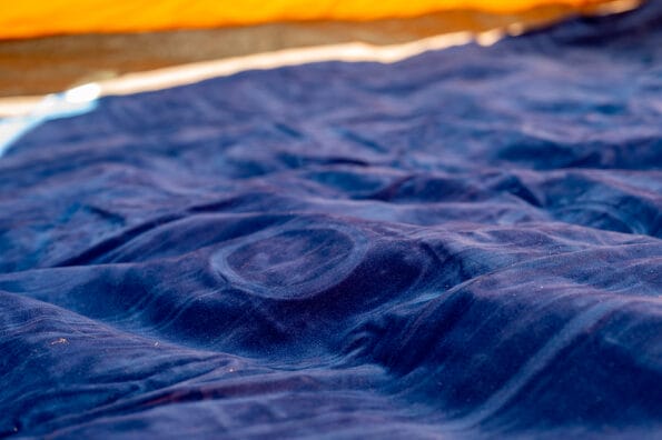 Selective focus of an inflatable air mattress on the floor of a tent being filled up.
