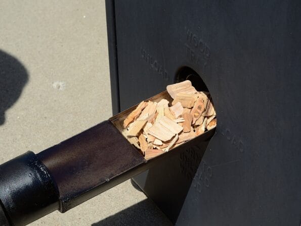Putting Hickory Wood Chips in a Barbecue BBQ Smoker