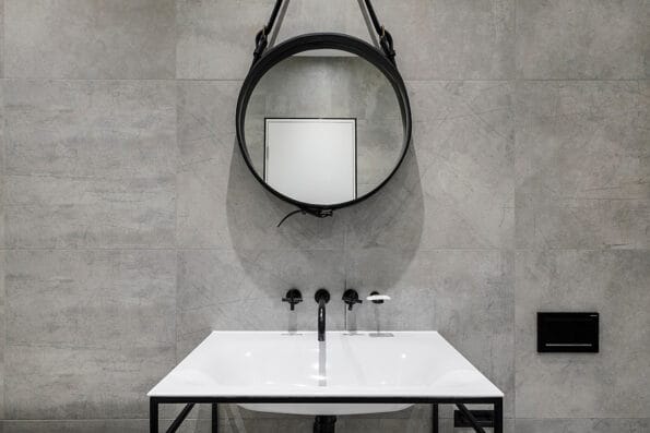 modern bathroom detail in neutral colours with black fixtures and round mirror