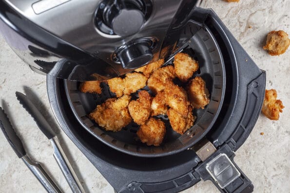 Close up flat lay image of an air fryer oven on kitchen countertop. This offers fast and easy crispy food with little or no fat by circulating hot air inside the basket. A healthy snack alternative.