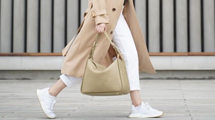 Carrying the WIT Bag in beige and walking across the street