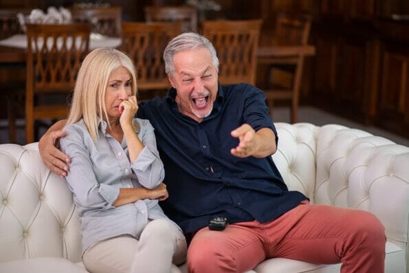 Man having a good laughter, his wife cries while watching the same tv program, lack of empathy concept