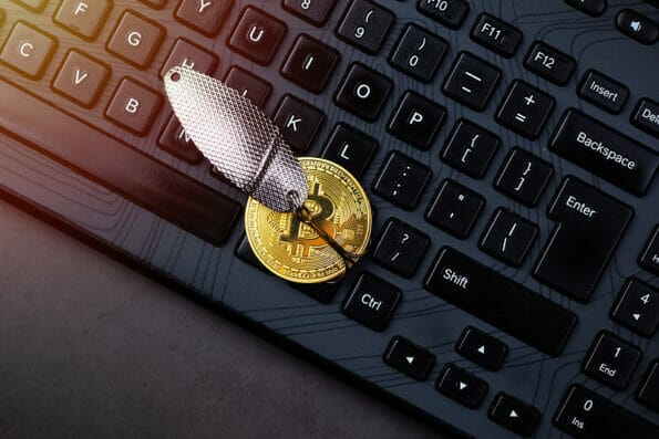 Bitcoin coin on a hook over the keyboard. Concept catching money, money scam, cryptology scam concept