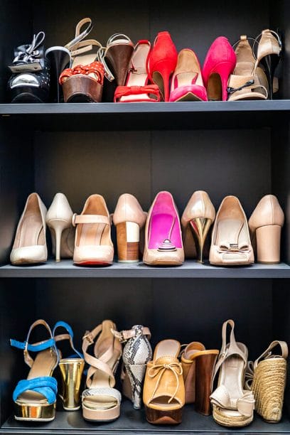 Gray closet shelves full of fashion female shoes on heels pair storage organization of cupboard