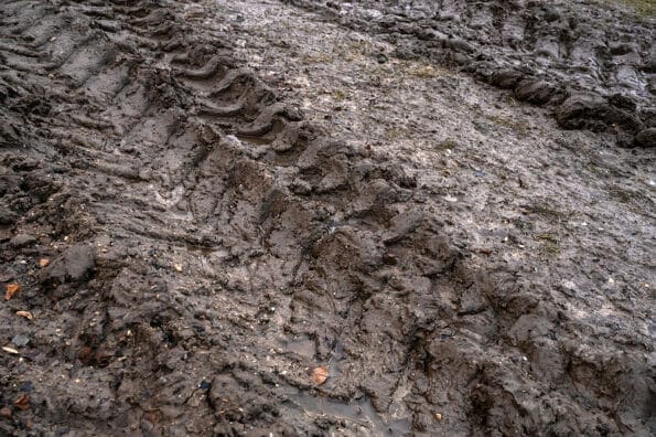 Close-up of tire tracks on muddy rural dirt road in late autumn. Off-road, wild dirt trail showing difficulties of moving people in rural areas during rainy season