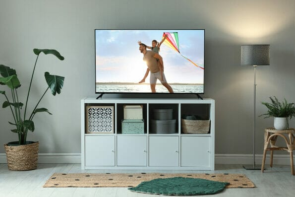Modern TV set on wooden stand in room