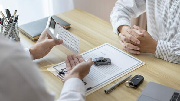 Selling cars, Car dealership or sales manager offers the sale of a car and explains the terms of signing a car purchase and insurance contract, Finance and after-sales service concept.
